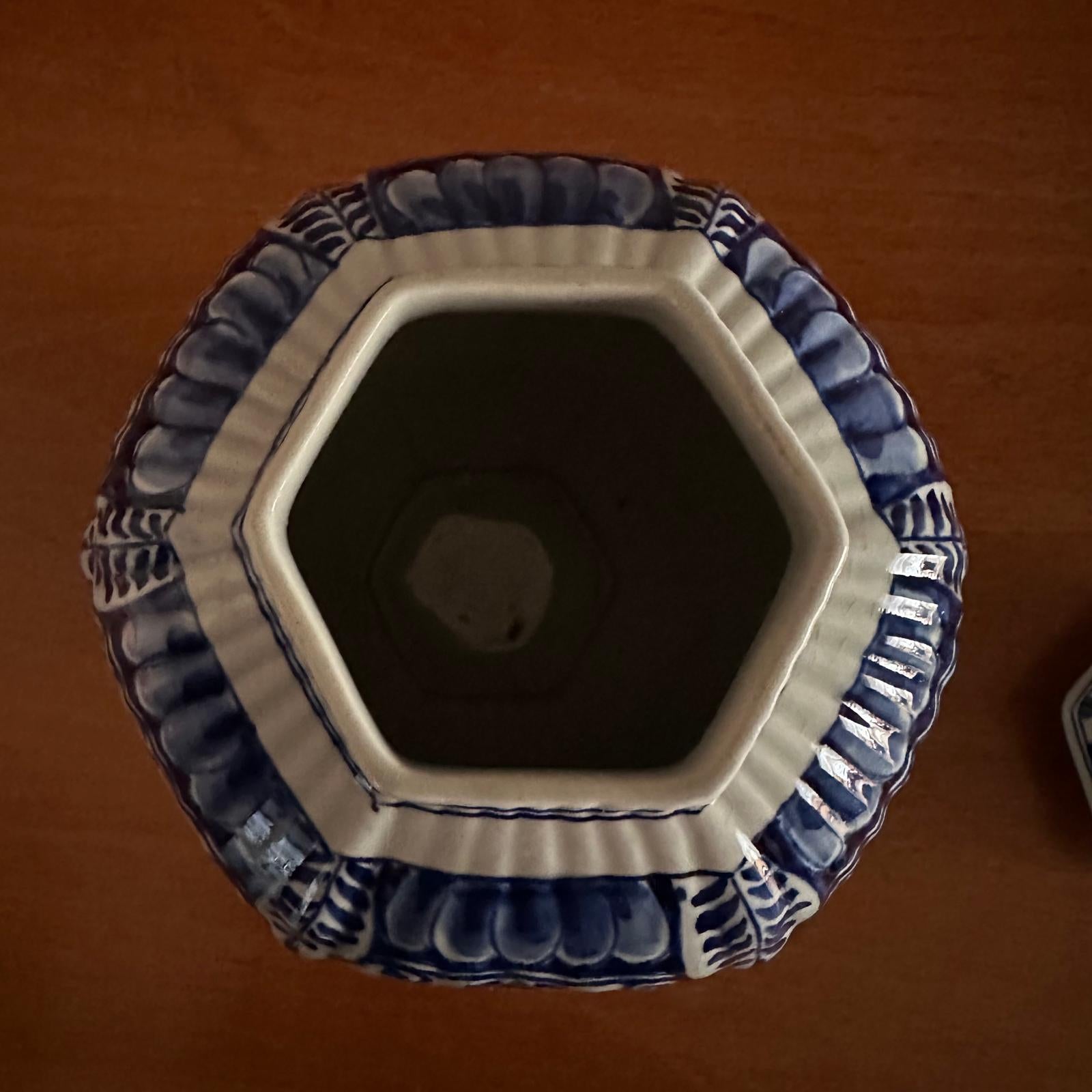 Hexagonal ceramic vase with blue and white patterns on a brown background