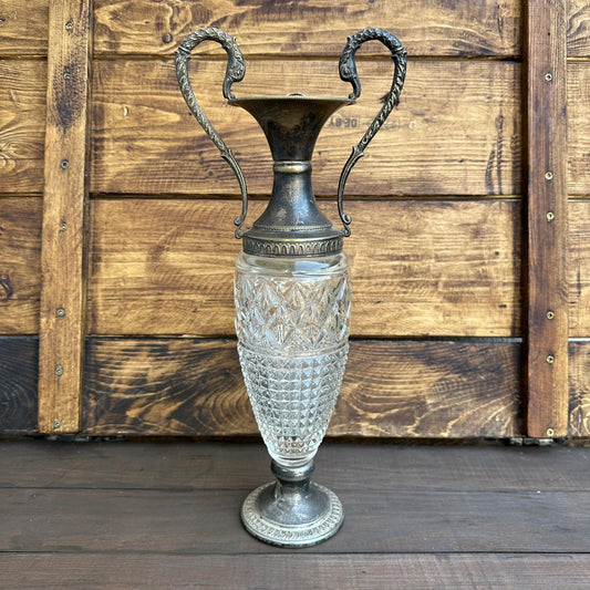 Decorative vase with crystal body and metal top against a wooden background