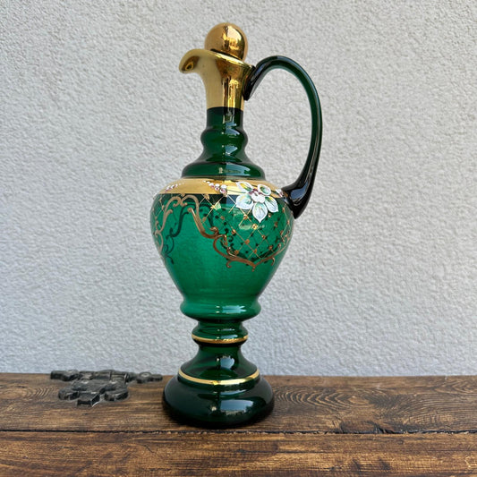 Decorative green pitcher with gold accents on a wooden surface