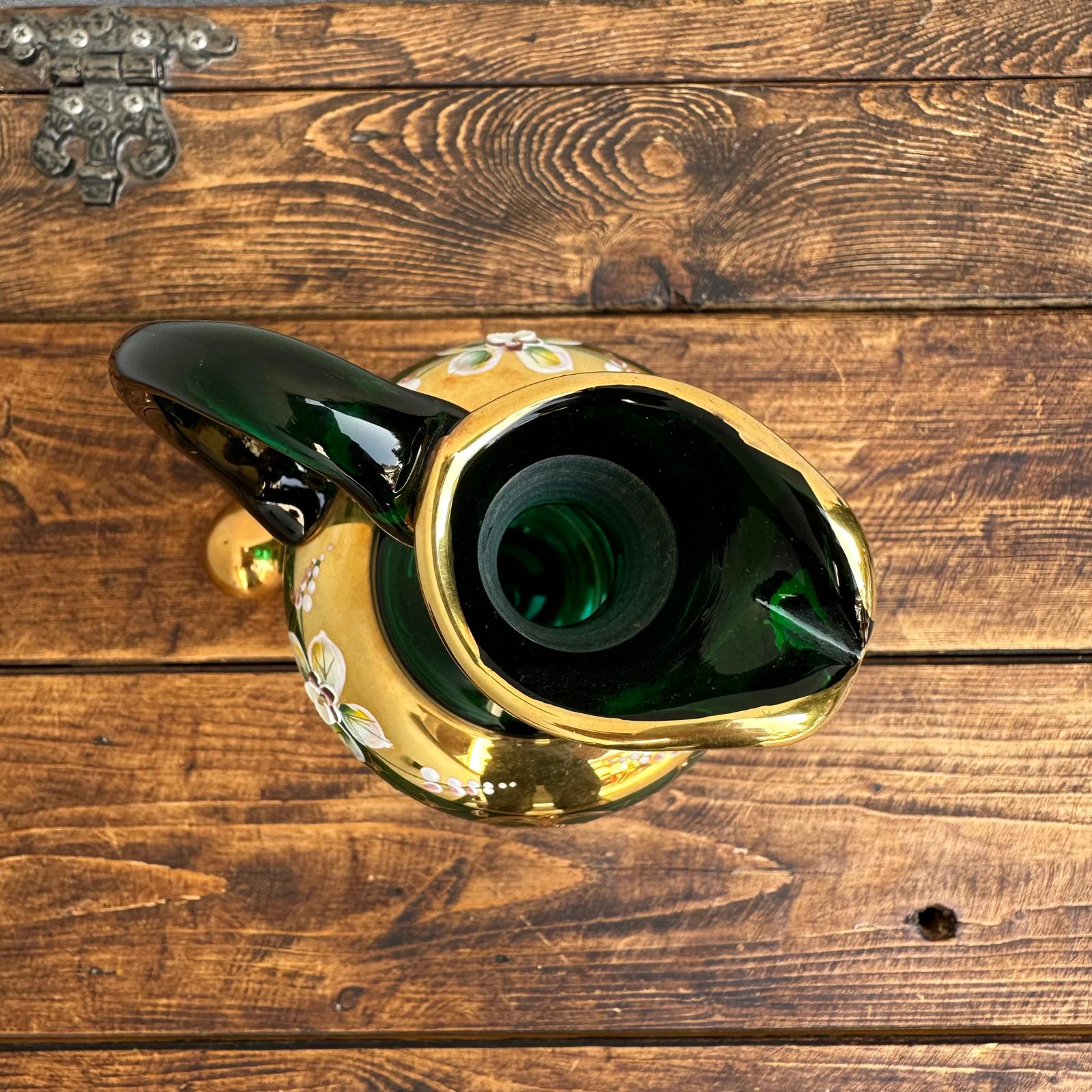 Green glass bottle with gold accents on a wooden surface