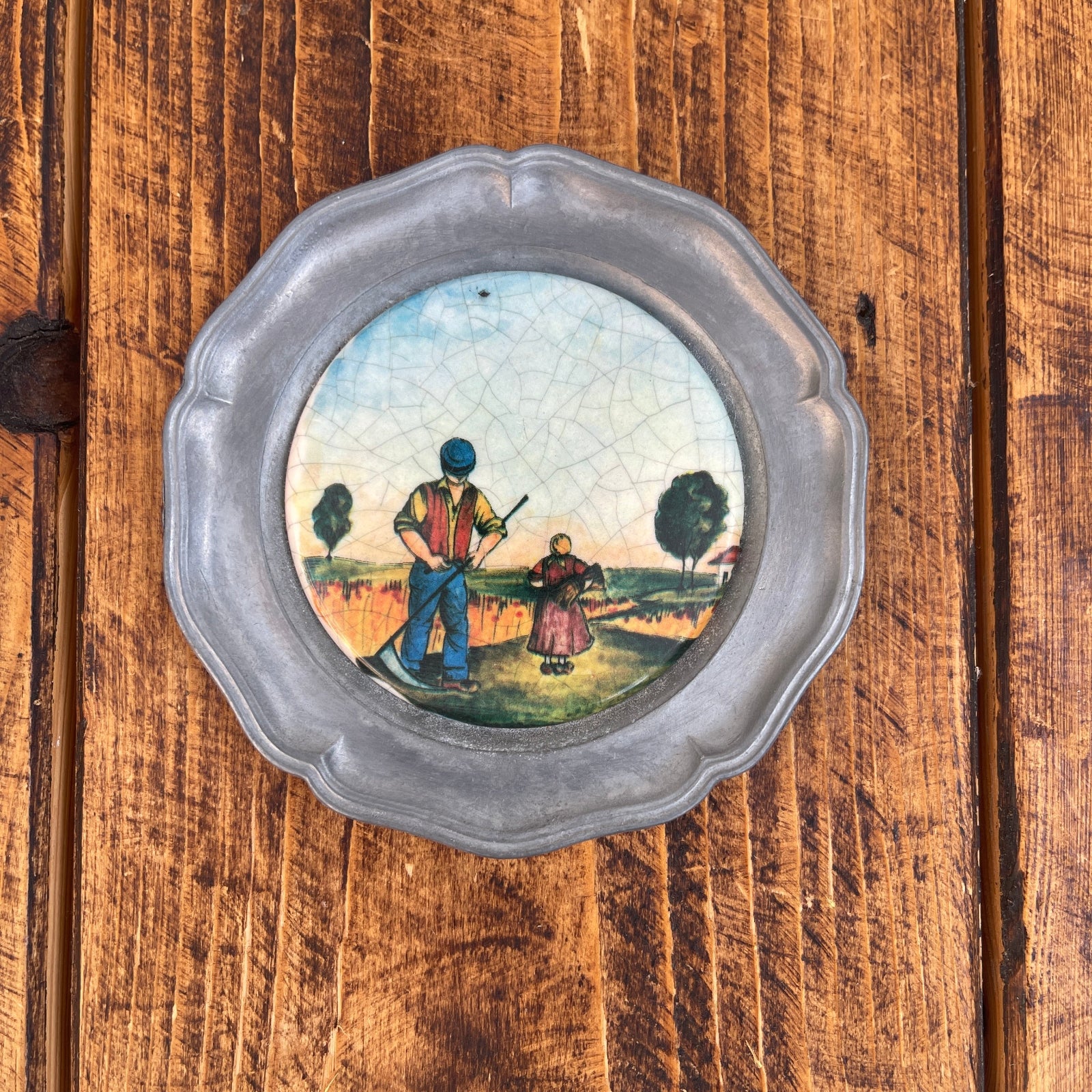 Decorative plate with a scenic painting of two people on a wooden surface