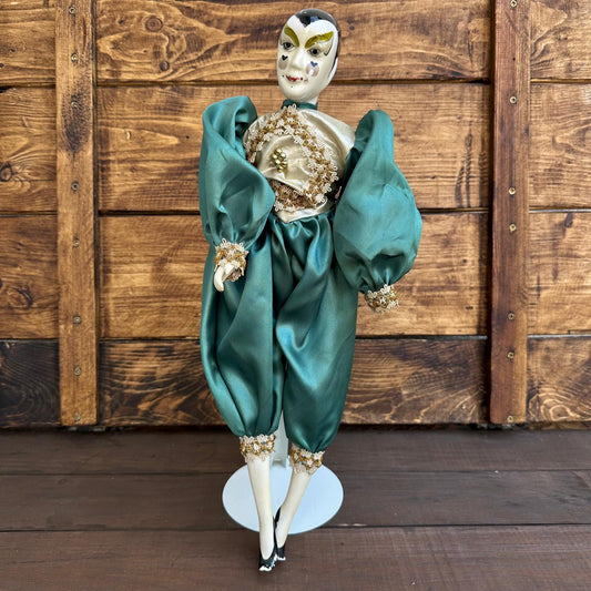 Traditional Japanese doll with green outfit and white face against a wooden background
