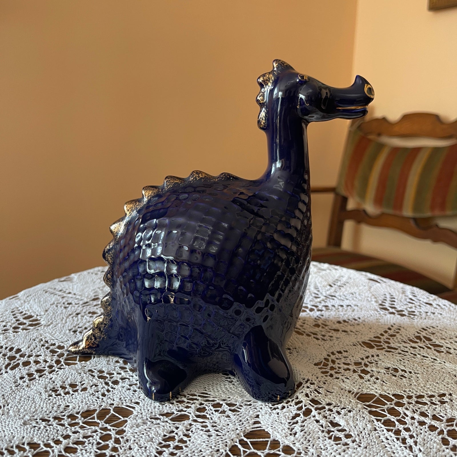 Blue ceramic dragon figurine on a lace tablecloth with a blurred background