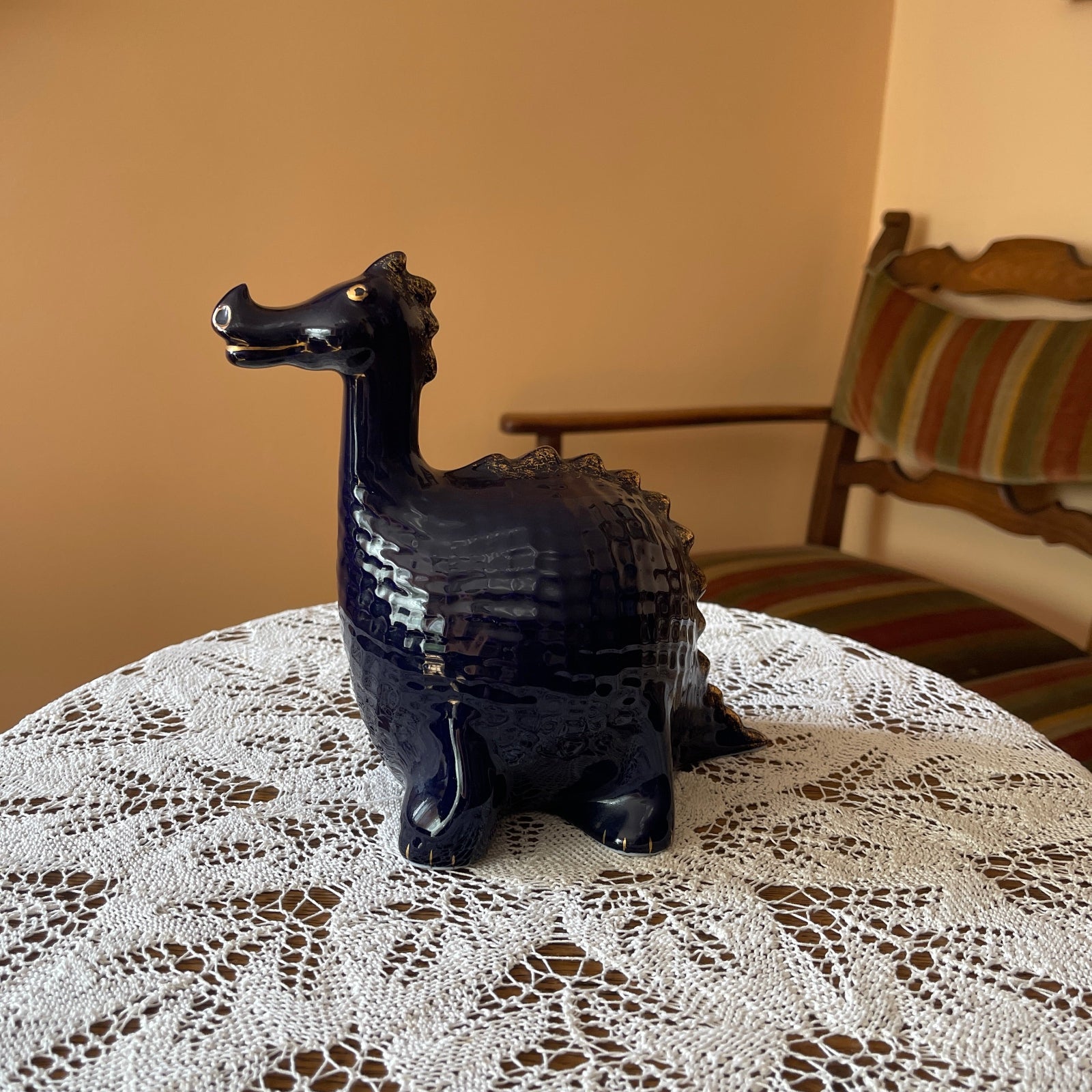 Cobalt dragon figurine on a lace tablecloth with a chair in the background