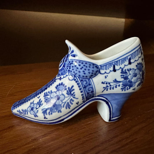 Ceramic shoe with blue floral patterns on a wooden surface