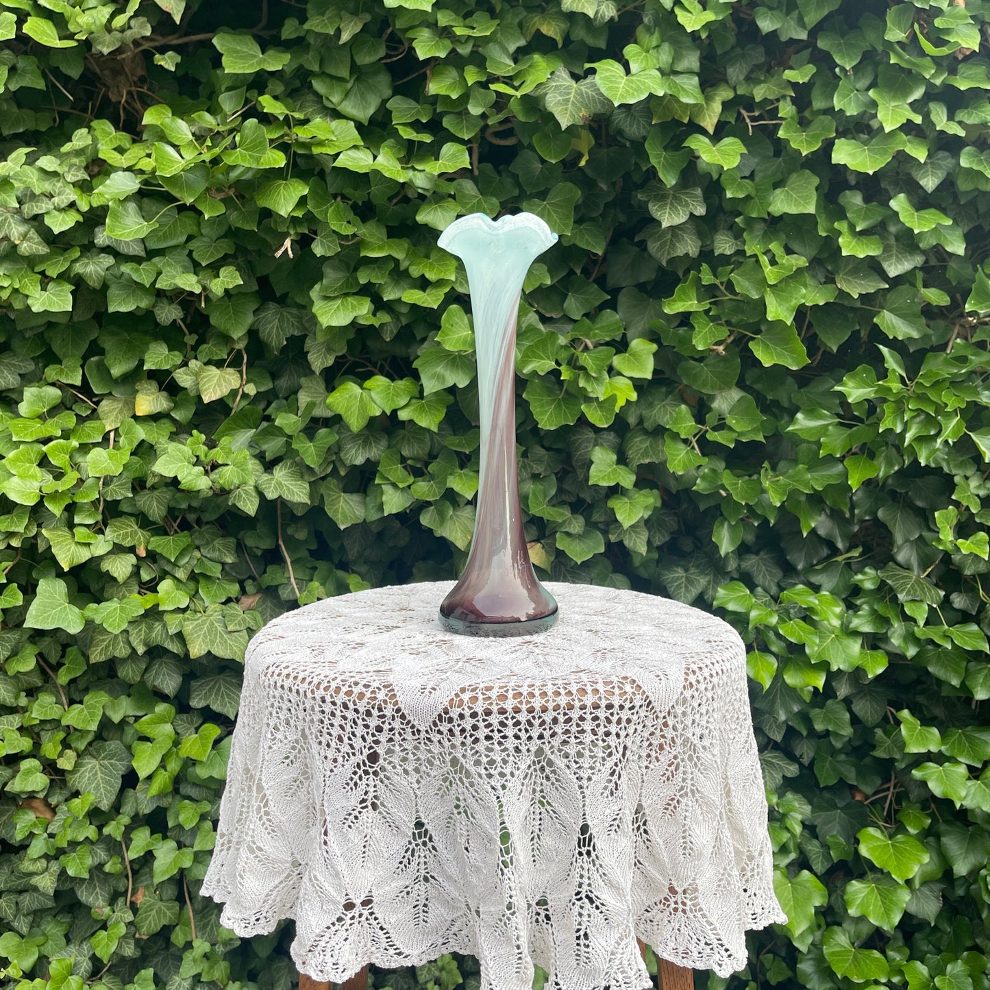 Decorative vase on a lace tablecloth with a green leafy background