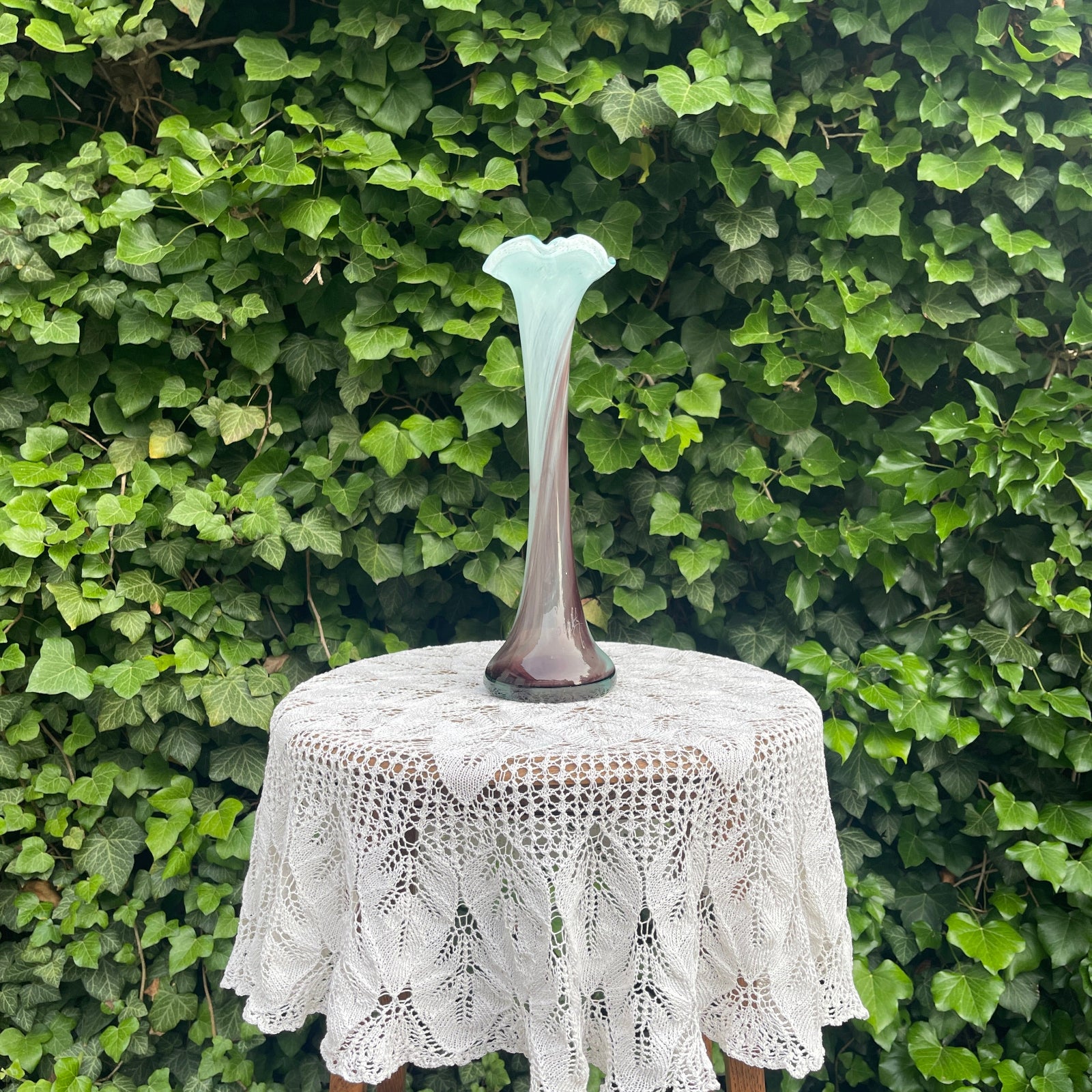 Decorative vase on a lace tablecloth with a green leafy background