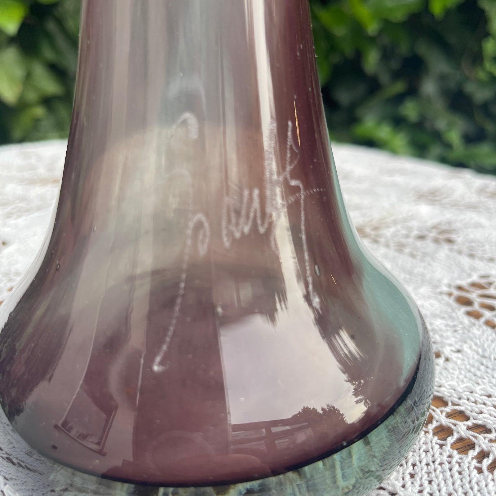 Brown glass vase with engraved text on a textured surface